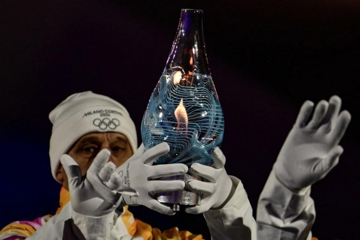 Italy's 1994 Winter Olympics 4×10km cross-country ski relay gold-medal winning team carry the Olympic flame within Murano glass during the closing ceremony of the Milano Cortina 2026 Winter Olympic Games at the Verona Arena in Verona, northern Italy, on February 22, 2026. Stefano RELLANDINI / AFP
