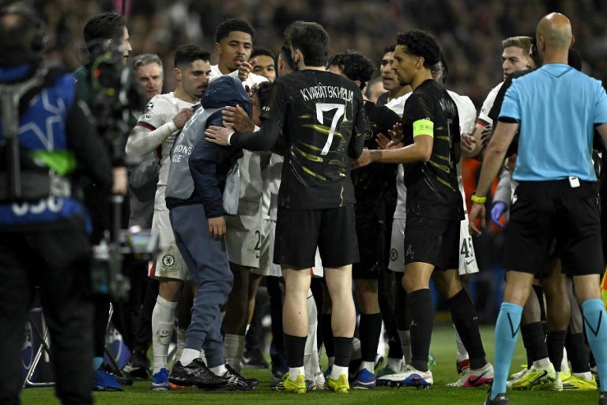 Chelsea's Portuguese forward #07 Pedro Neto (L) tends to a ballboy after he pushed him during the UEFA Champions League round of 16 first leg football match between Paris Saint-Germain (PSG) and Chelsea at the Parc des Princes stadium in Paris on March 11, 2026. JULIEN DE ROSA / AFP
