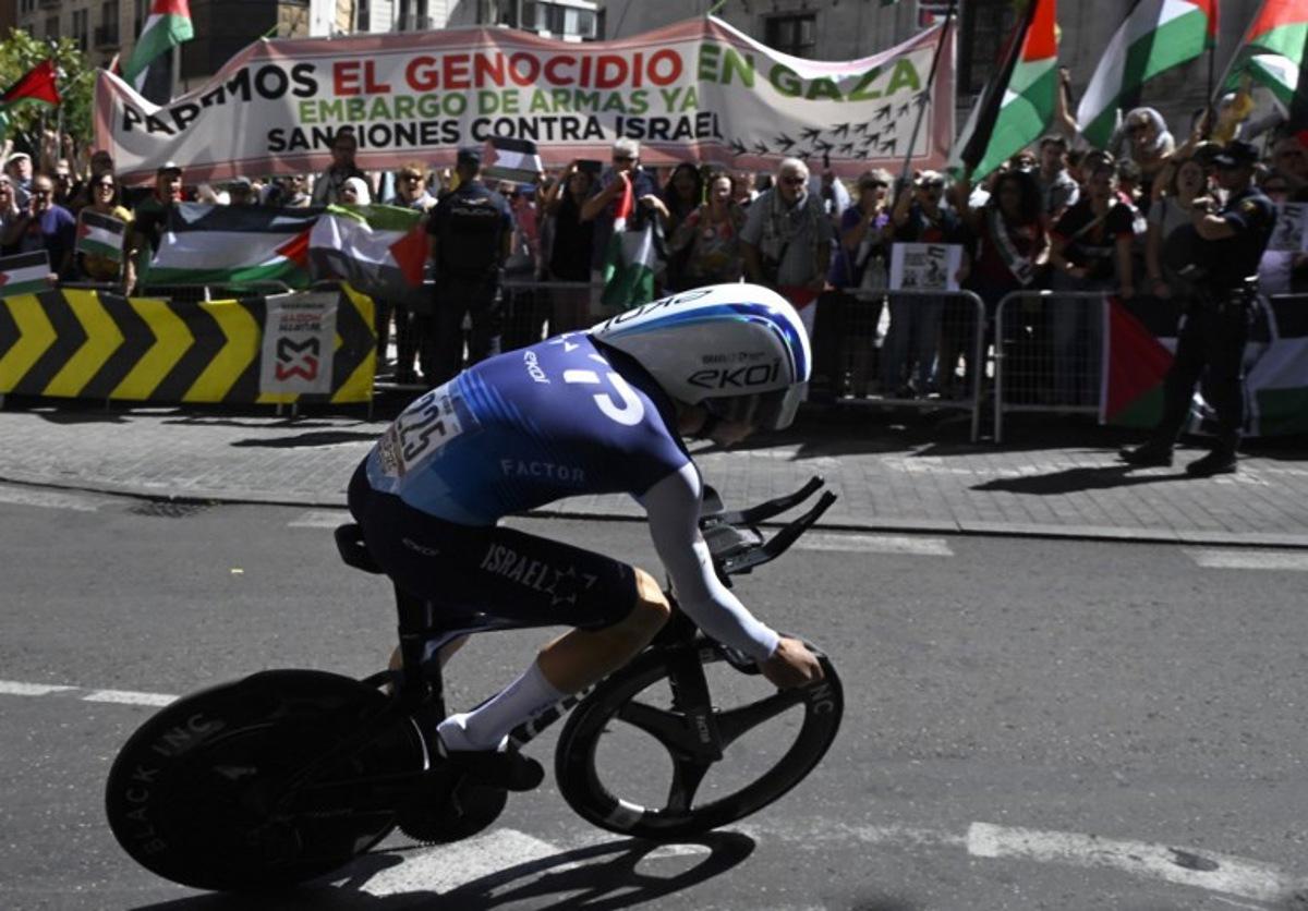 Pro-Palestinians protesters wave Palestinian flags as Team Israel Premier Tech's Israeli rider Nadav Raisberg competes during the 18th stage of the Vuelta a Espana, a 26 km race against the clock between Valladolid and Valladolid, on September 11, 2025. Miguel RIOPA / AFP