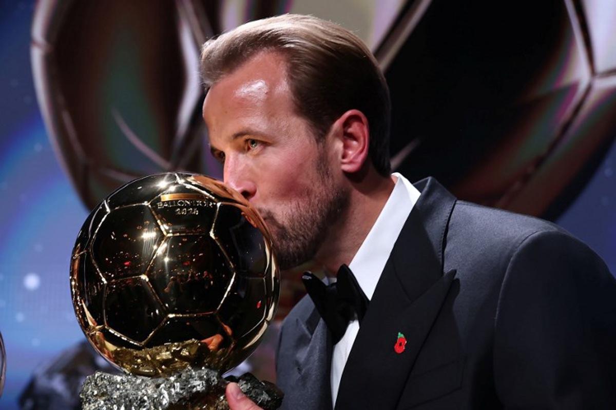 England and Bayern Munich forward Harry Kane kisses the trophy on stage after receiving the Ballon d'Or award for the best male footballer during the 2026 Ballon d'Or France Football award ceremony at the Palladium Theatre in London on October 26, 2026. FRANCK FIFE / AFP