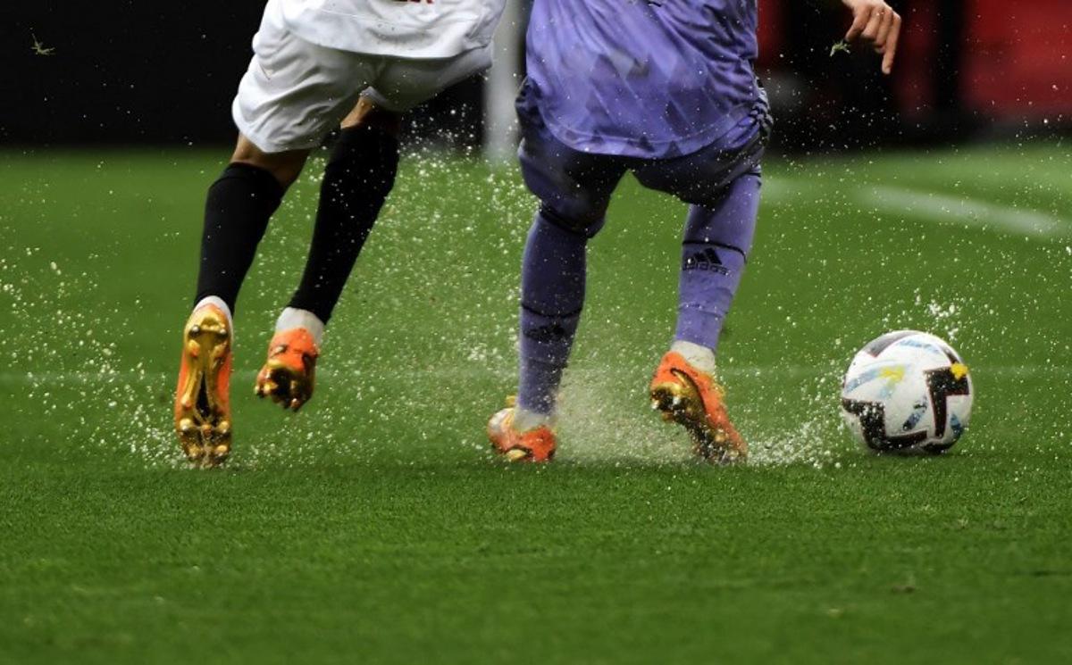 Players run on a waterlogged pitch during the Spanish league football match between Sevilla FC and Real Madrid CF at the Ramon Sanchez Pizjuan stadium in Seville on May 27, 2023. CRISTINA QUICLER / AFP