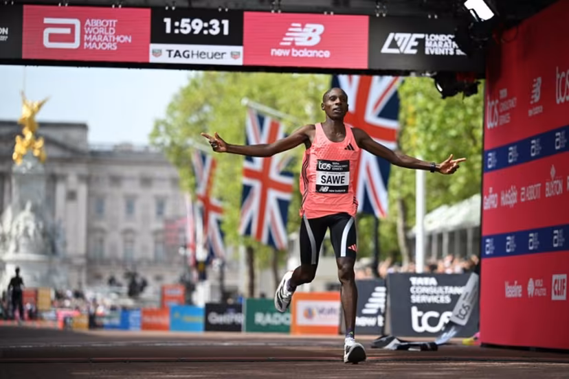 Kenya's Sabastian Sawe crosses the line to win the men's race in a new world record time at the 2026 London Marathon in central London on April 26, 2026. Kenya's Sabastian Sawe broke the two-hour mark for the first time in history on Sunday in winning the London Marathon. JUSTIN TALLIS / AFP