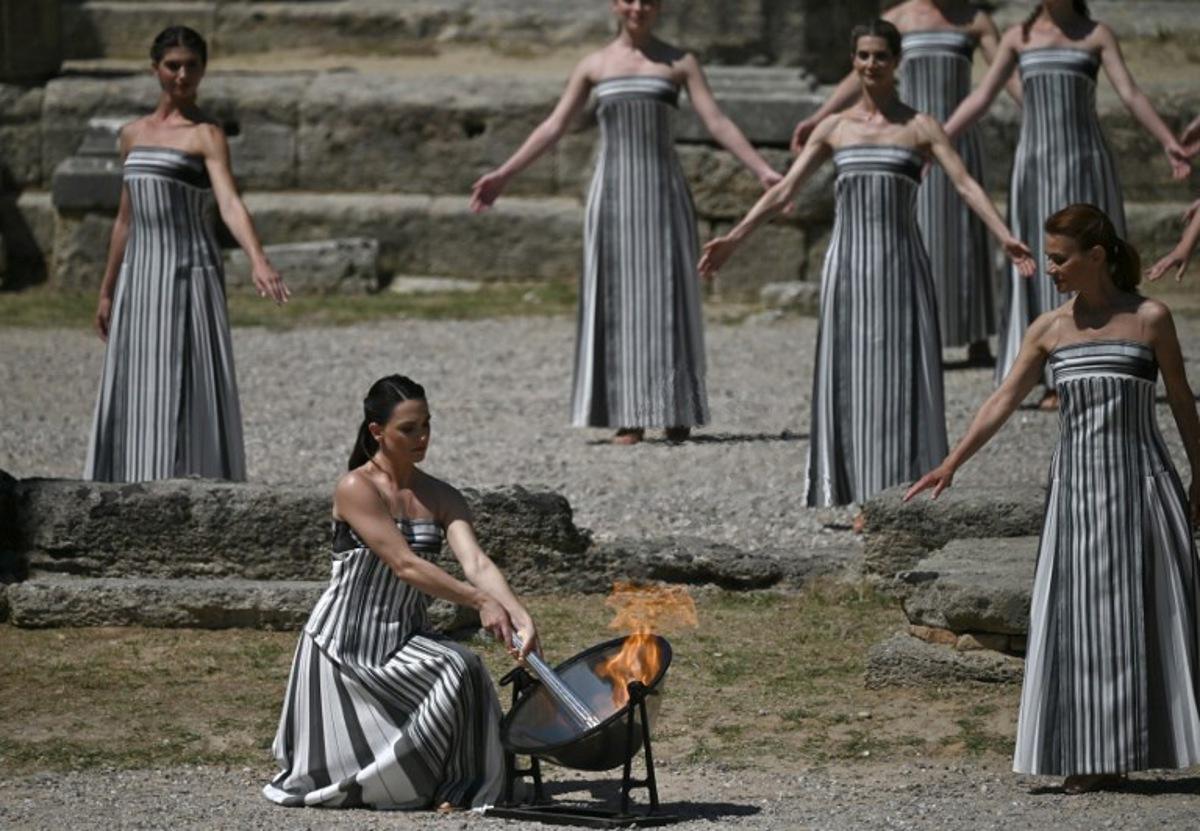 Greek actress Mary Mina, in the role of the High Priestess, lights the torch during the rehearsal of the flame lighting ceremony for the Paris 2024 Olympic Games at the ancient temple of Hera on the Olympia archeological site, birthplace of the ancient Olympics in southern Greece, on April 15, 2024. Valerie GACHE / AFP