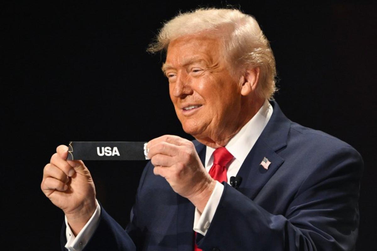 US President Donald Trump shows the card reading USA during the draw for the 2026 FIFA Football World Cup taking place in the US, Canada and Mexico, at the Kennedy Center, in Washington, DC, on December 5, 2025. Mandel NGAN / POOL / AFP