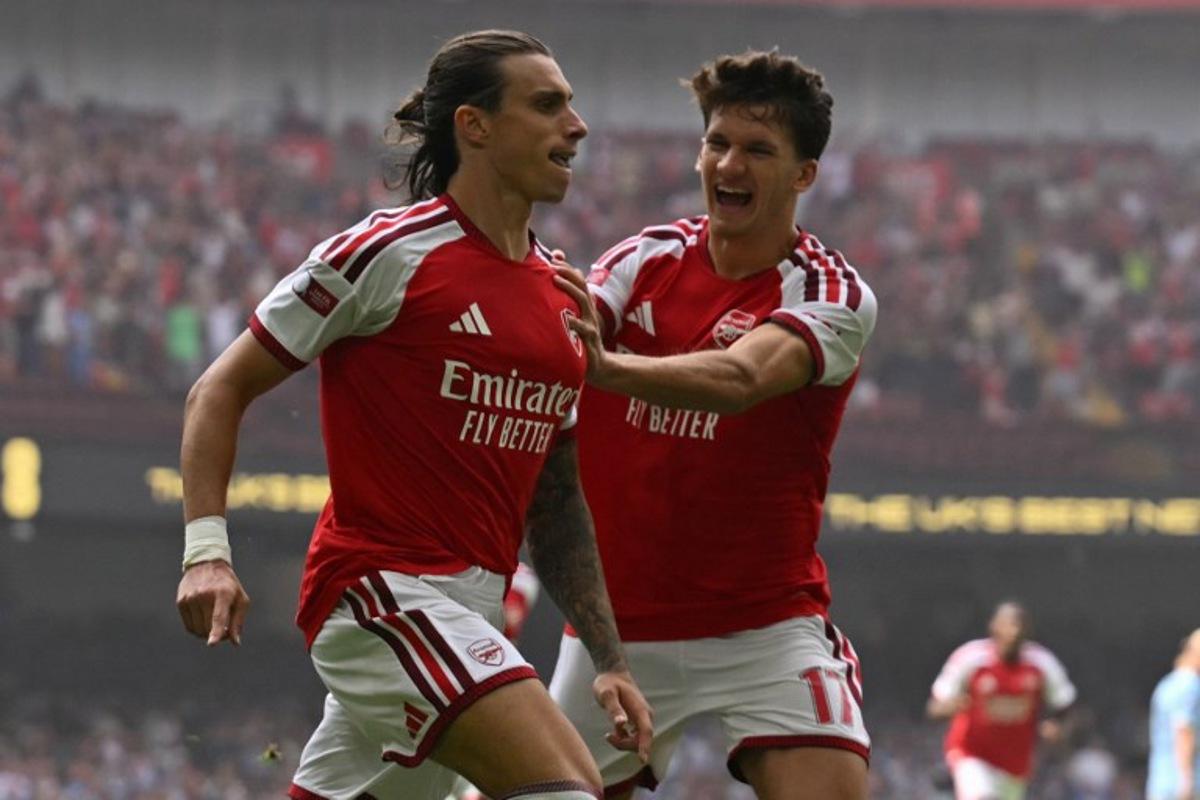 Arsenal's Italian defender #33 Riccardo Calafiori (L) celebrates with Arsenal's Greek striker #17 Christos Tzolis (R) after scoring the opening goal of the English FA Community Shield football match between Arsenal and Manchester City at The Principality Stadium, in Cardiff, south Wales on August 16, 2026. Glyn KIRK / AFP