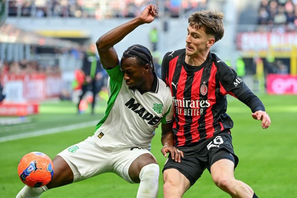 Sassuolo's Canadian midfielder #90 Ismaël Koné fights for the ball with AC Milan's Belgian midfielder #56 Alexis Saelemaekers during the Italian Serie A football match between AC Milan and Sassuolo at the San Siro Stadium in Milan, Italy on December 14, 2025. Piero CRUCIATTI / AFP