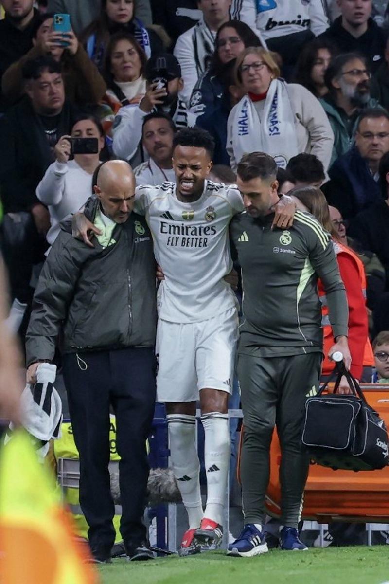 Real Madrid's Brazilian defender #03 Eder Militao walks off with assistance after sustaining an injury during the Spanish league football match between Real Madrid CF and RC Celta de Vigo at the Santiago Bernabeu Stadium in Madrid on December 7, 2025. Thomas COEX / AFP