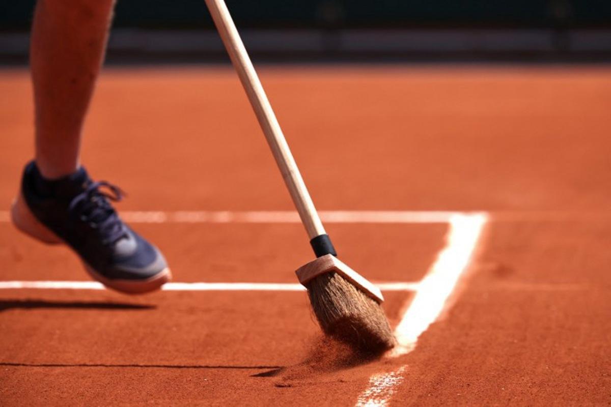 A staff member sweeps the clay on a court during the French Open tennis tournament at the Roland Garros Complex in Paris on May 26, 2024. Anne-Christine POUJOULAT / AFP