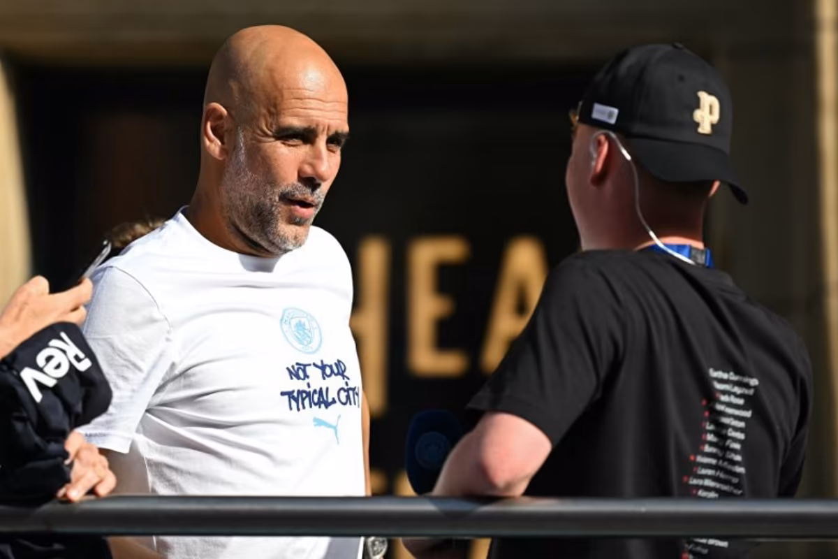 Departing Manchester City manager Pep Guardiola hops onto the bus with his youth players at the start of the winner's parade by the Manchester City team after their victories in the two domestic cup competitions on May 25, 2026, in central Manchester, north-west England. Paul ELLIS / AFP