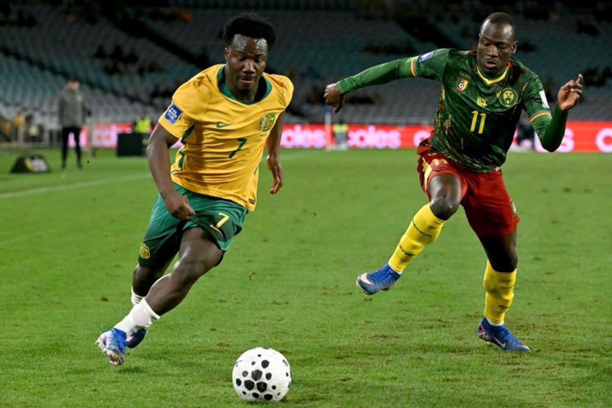 Australia's Nestory Irankunda (L) runs with the ball past Cameroon's Saidou Alioum Moubarak (R) during the international friendly football match between Australia and Cameroon at Stadium Australia in Sydney on March 27, 2026. SAEED KHAN / AFP