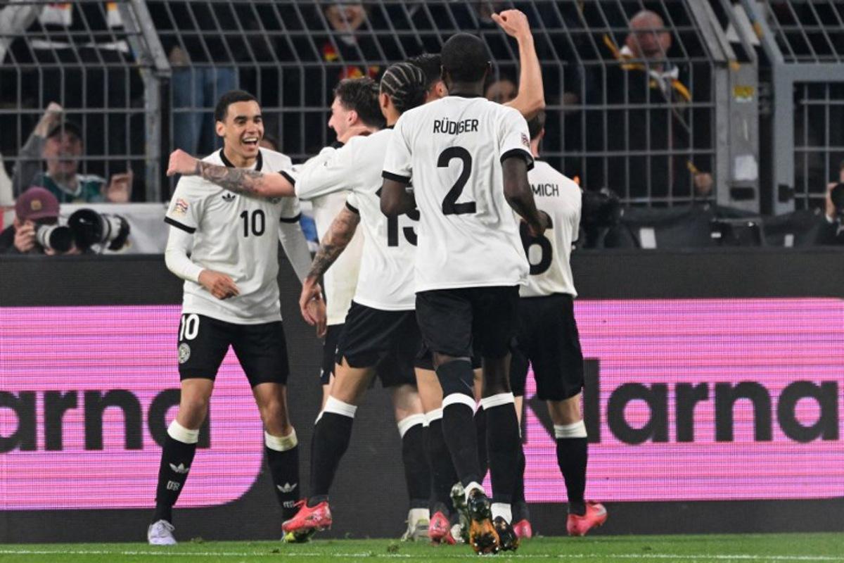 Germany's midfielder #10 Jamal Musiala (L) celebrates scoring the 2-0 goal with his teammates during the UEFA Nations League quarter-final second leg football match Germany v Italy at the Signal Iduna Park stadium in Dortmund, western Germany on March 23, 2025. Kirill KUDRYAVTSEV / AFP
