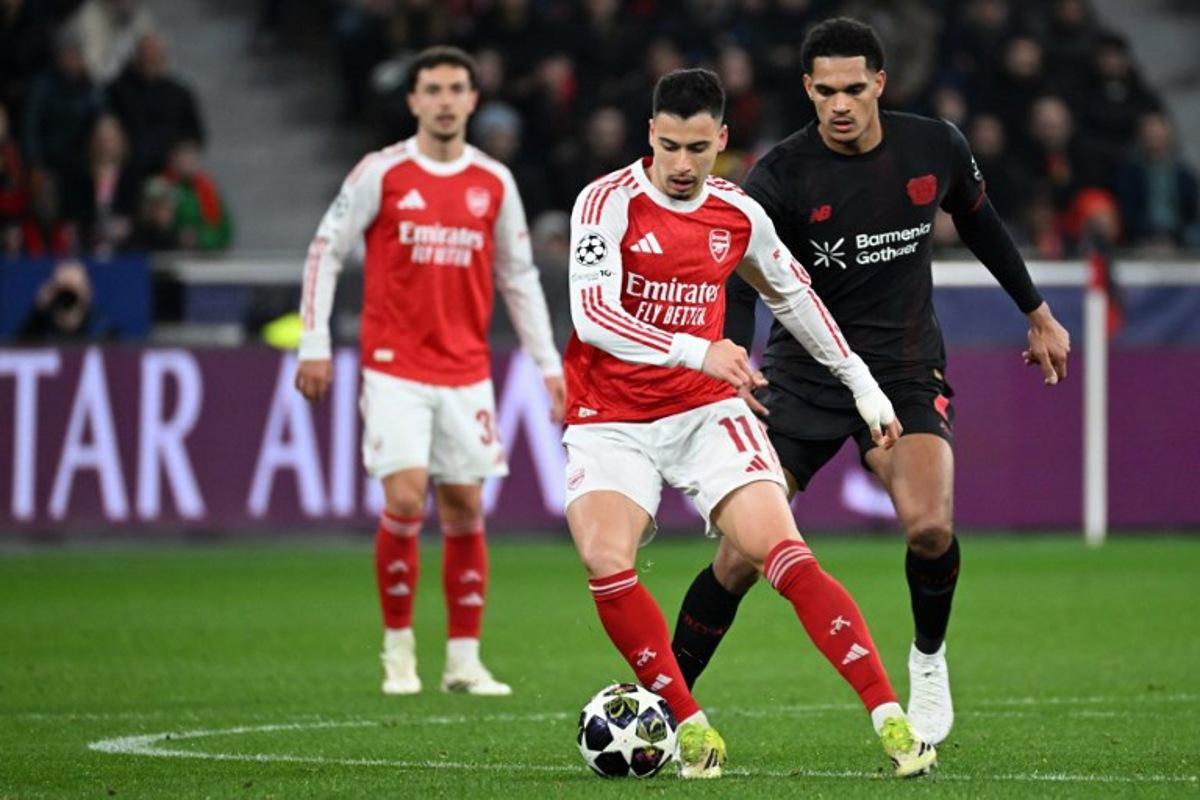 Bayer Leverkusen's French forward #11 Martin Terrier (C) and Bayer Leverkusen's English defender #04 Jarell Quansah (R) vie for the ball during the UEFA Champions League, Last 16, first-leg football match Bayer 04 Leverkusen vs Arsenal in Leverkusen, western Germany, on March 11, 2026. UWE KRAFT / AFP