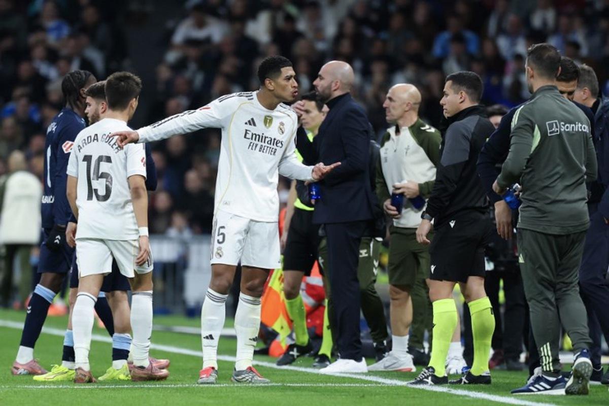 Real Madrid's English midfielder #05 Jude Bellingham (C) argues with an assistant referee after receiving a yellow card during the Spanish league football match between Real Madrid CF and RC Celta de Vigo at the Santiago Bernabeu Stadium in Madrid on December 7, 2025. Thomas COEX / AFP
