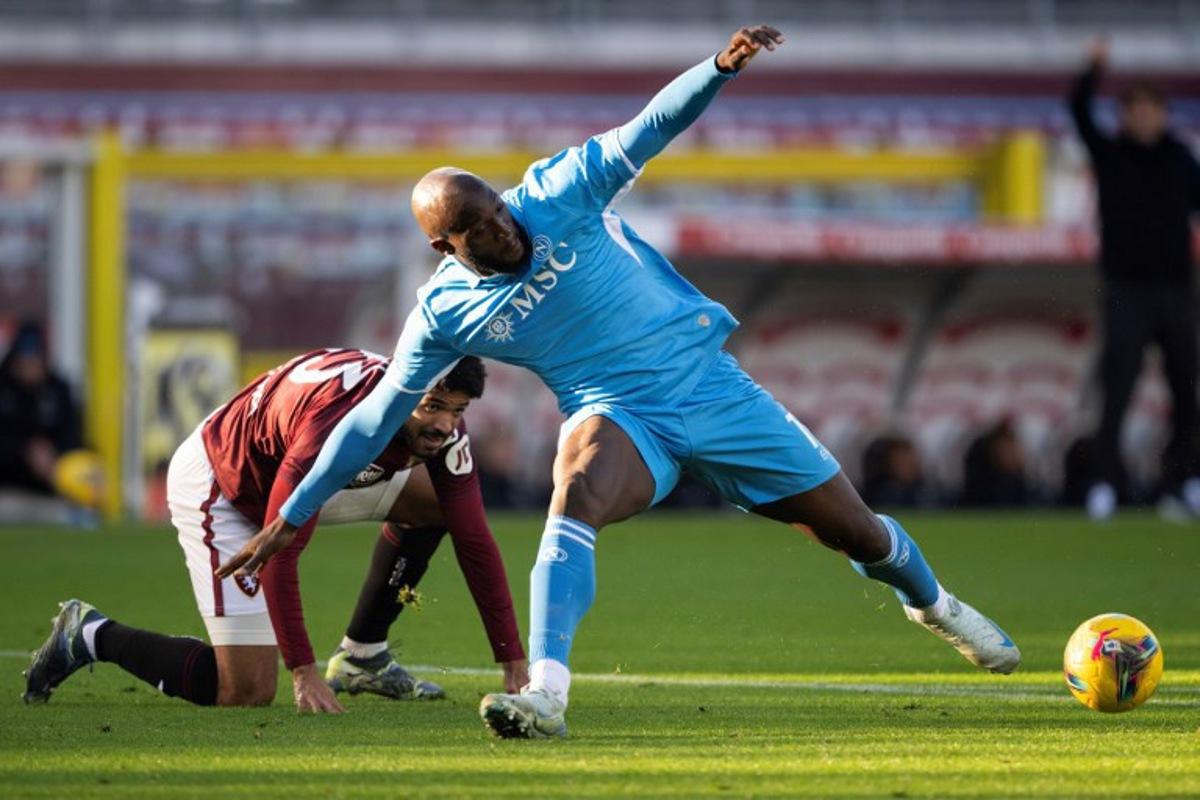 Napoli's Belgian forward #11 Romelu Lukaku (R) stretches to control the ball ahead of Torino's Equatorial Guinea defender #23 Saul Basilio Coco-Bassey Oubina (L) during the Italian Serie A football match between Torino FC and SSC Napoli at the Olympic Grande Torino Stadium in Turin on December 1, 2024. MARCO BERTORELLO / AFP
