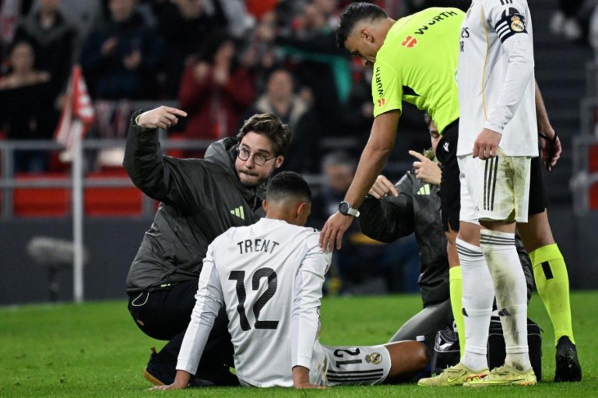 Real Madrid's English defender #12 Trent Alexander-Arnold receives medical assistance after sustaining an injury during the Spanish league football match between Athletic Club Bilbao and Real Madrid CF at the San Mames stadium in Bilbao on December 3, 2025. ANDER GILLENEA / AFP