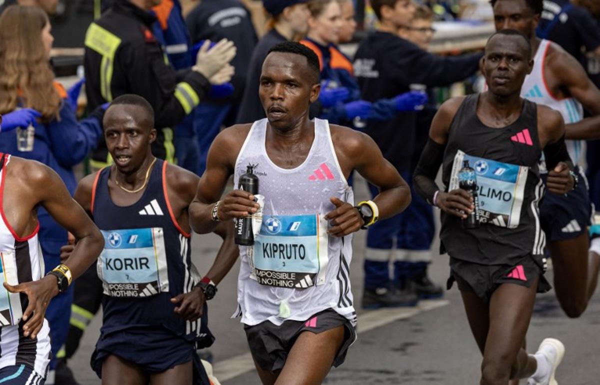 Kenya's Amos Kipruto (C) and Kenya's Ronald Korir (L) pass a water station at the 22km mark as they compete in the men's race of the Berlin Marathon on September 24, 2023 in Berlin, Germany. Odd ANDERSEN / AFP