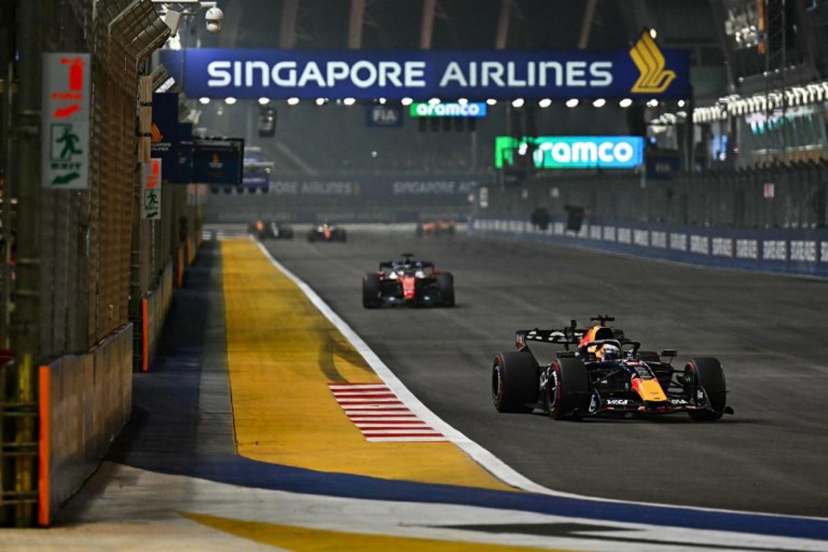Red Bull Racing's Dutch driver Max Verstappen (R) drives in front of Ferrari's Monegasque driver Charles Leclerc during the Formula One Singapore Grand Prix at the Marina Bay Street Circuit in Singapore on October 11, 2026. Lillian SUWANRUMPHA / AFP