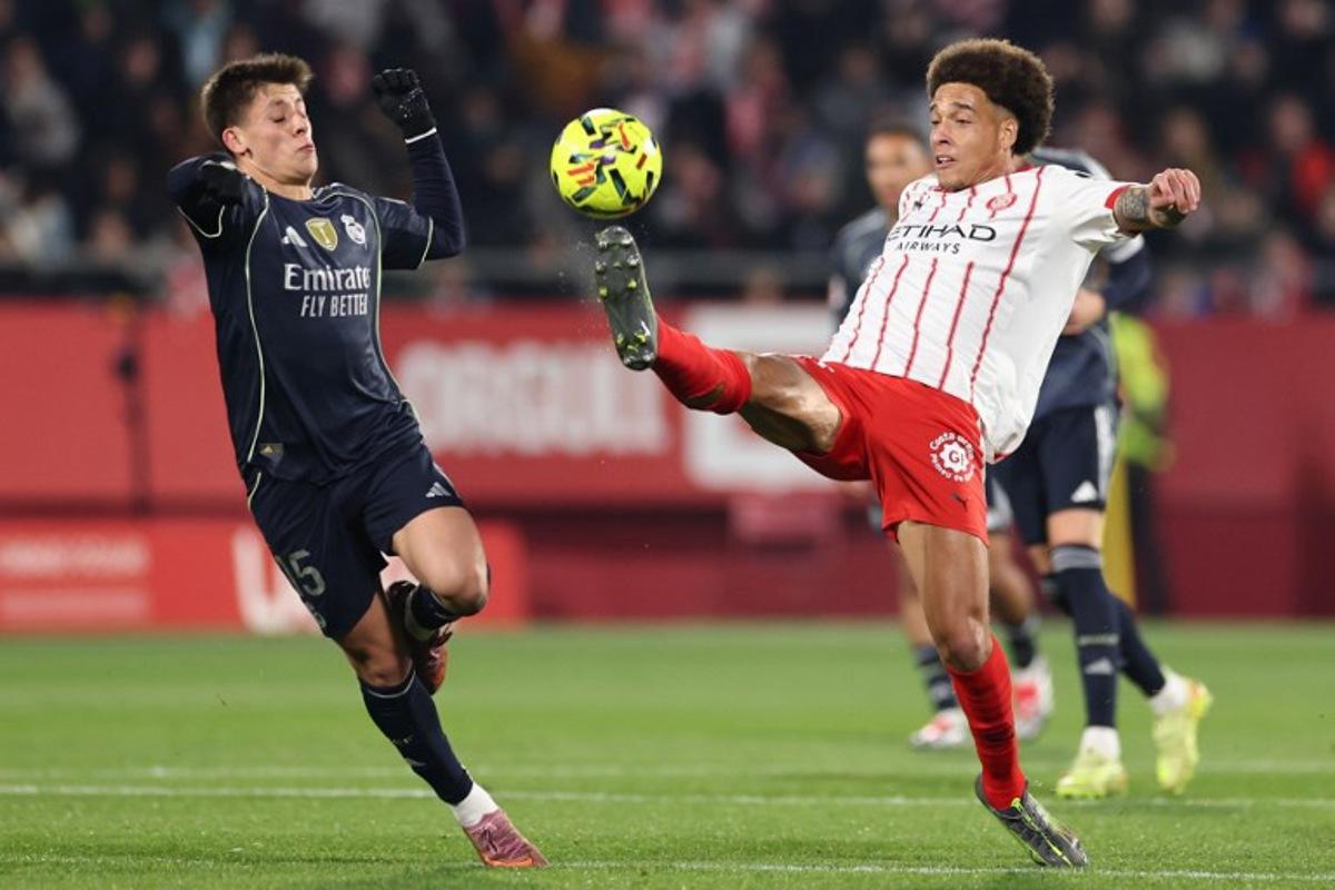 Real Madrid's Turkish midfielder #15 Arda Guler (L) fights for the ball with Girona's Belgian defender #20 Axel Witsel during the Spanish league football match between Girona FC and Real Madrid CF at Montilivi Stadium in Girona on November 30, 2025. Josep LAGO / AFP