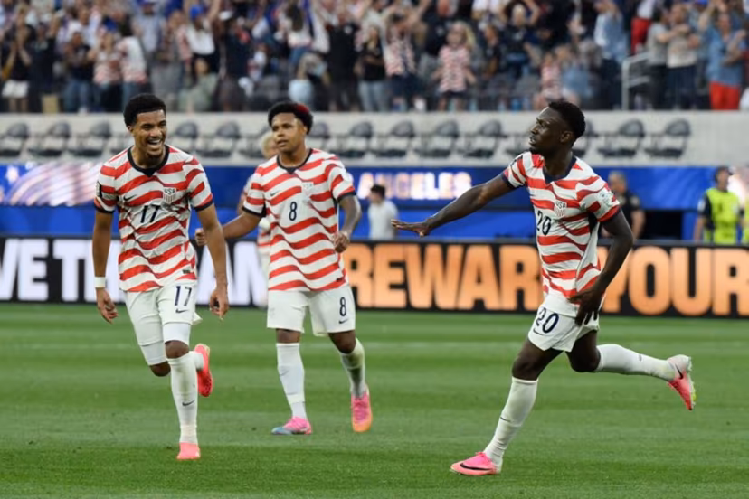 US forward #20 Folarin Balogun (R) celebrates scoring his team's third goal during the 2026 World Cup Group D football match between USA and Paraguay at the Los Angeles Stadium in Inglewood on June 12, 2026. Patrick T. Fallon / AFP