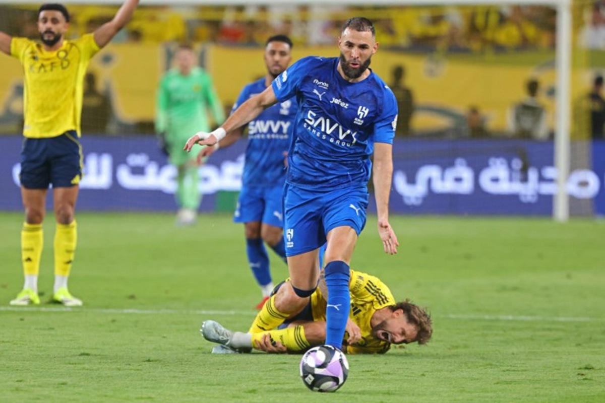 Nassr's Spanish defender #26 Inigo Martinez (down) reacts as Al-Hilal French forward #90 Karim Benzema fights for the ball with during the Saudi Pro League football match between Al-Nassr and Al-Hilal at King Fahd Sports City Stadium in Riyadh on May 12, 2026. Fayez NURELDINE / AFP