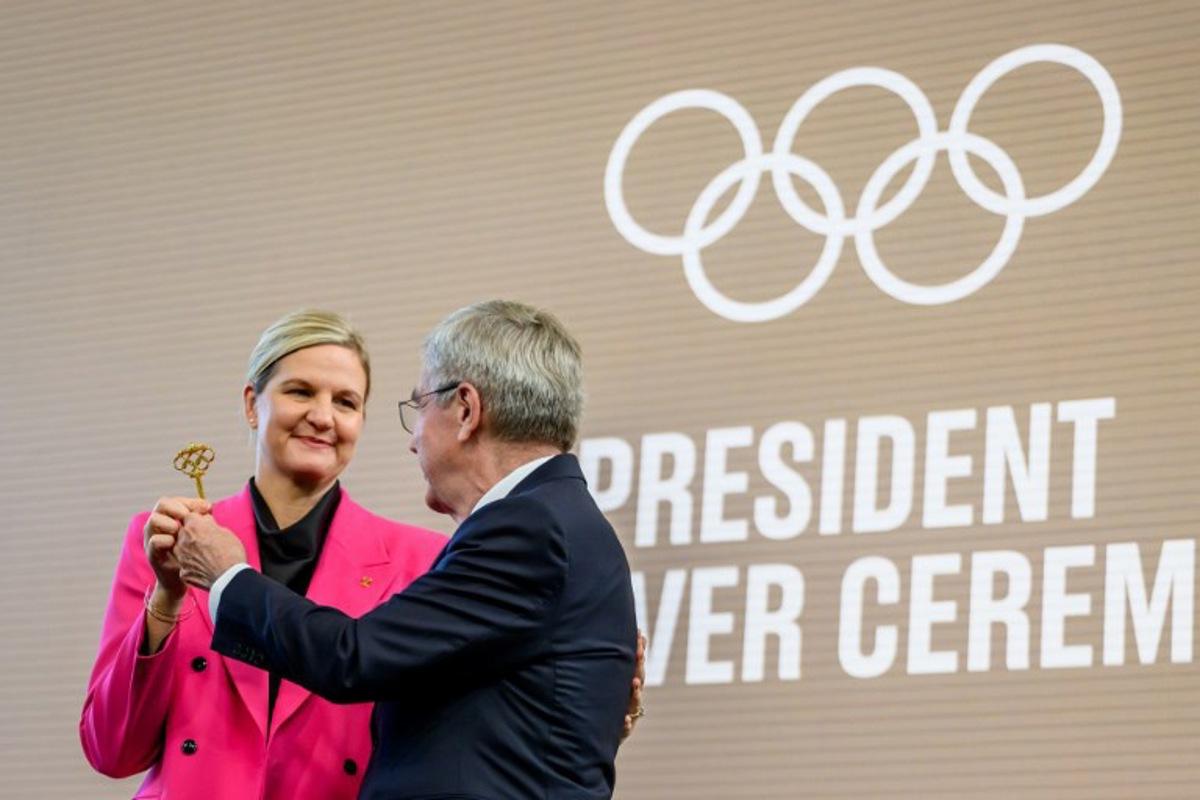 International Olympic Committee (IOC) President Kirsty Coventry (L) receives the key from outgoing IOC President Thomas Bach during a handover ceremony at Olympic House in Lausanne, Switzerland, on June 23, 2025. Zimbabwean swimmer who won seven Olympic medals, Kirsty Coventry, becomes the first woman to lead the Olympic movement. Fabrice COFFRINI / AFP