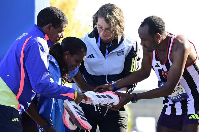 Ethiopia's Tigst Assefa (2L) is helped off the track after crossing the finish line to win the women's race of 52nd Berlin Marathon in Berlin, Germany on September 27, 2026. Ethiopian runner Tigst Assefa narrowly missed out on breaking the women's world record at the Berlin Marathon on Sunday, crossing the finish line with an injury after being on record pace throughout. John MACDOUGALL / AFP