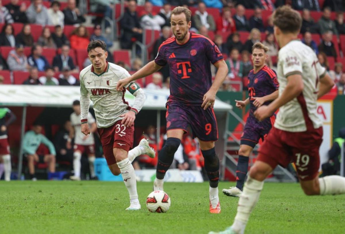 Bayern Munich's English forward #09 Harry Kane (C) and Augsburg's Swiss midfielder #32 Fabian Rieder (L) vie for the ball during the German first division Bundesliga football match between FC Augsburg and FC Bayern Munich in Augsburg, southern Germany on October 10, 2026. Karl-Josef HILDENBRAND / AFP