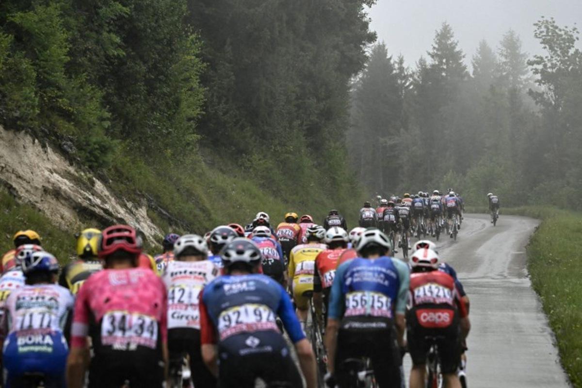 The pack of riders (peloton) cycles in the rain during the 20th stage of the 112th edition of the Tour de France cycling race, 184.2 km between Nantua and Pontarlier, in the Jura, eastern France, on July 26, 2025. Loic VENANCE / AFP