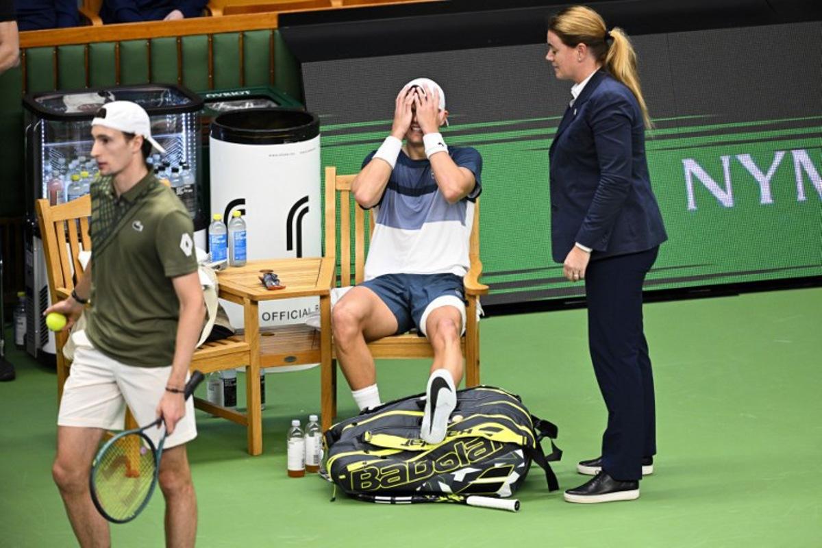 Denmark's Holger Rune (C) reacts after injurung his foot during the semi-final of the BNP Paribas Nordic Open tennis tournament against France's Ugo Humbert (L) at the Royal Swedish Tennis Hall in Stockholm, Sweden, on October 18, 2025. Anders WIKLUND / TT NEWS AGENCY / AFP
