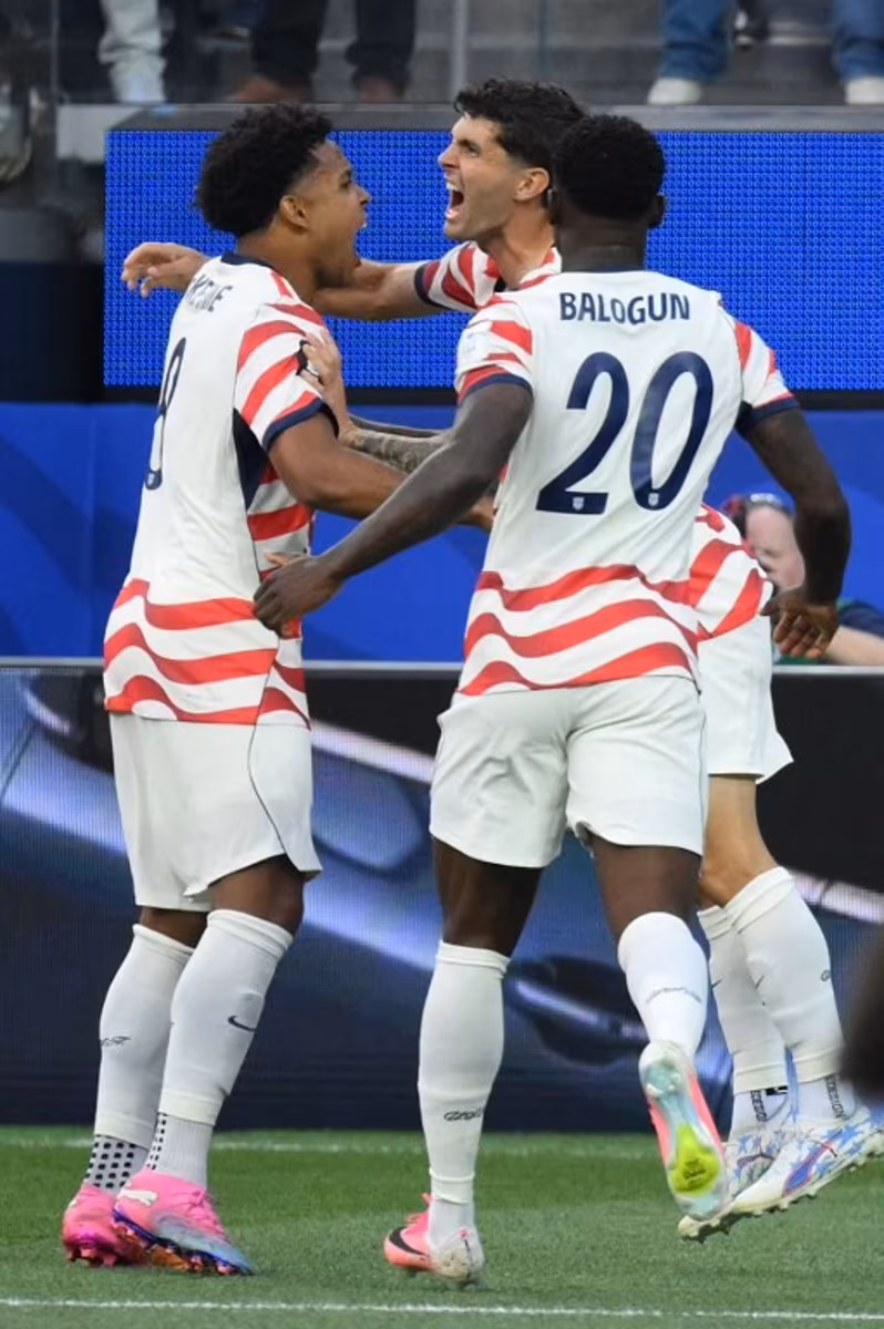 US forward #10 Christian Pulisic (C) celebrates with teammates after his team's first goal scored on own goal by Paraguay's midfielder #16 Damian Bobadilla (unseen) during the 2026 World Cup Group D football match between USA and Paraguay at the Los Angeles Stadium in Inglewood on June 12, 2026. Patrick T. Fallon / AFP