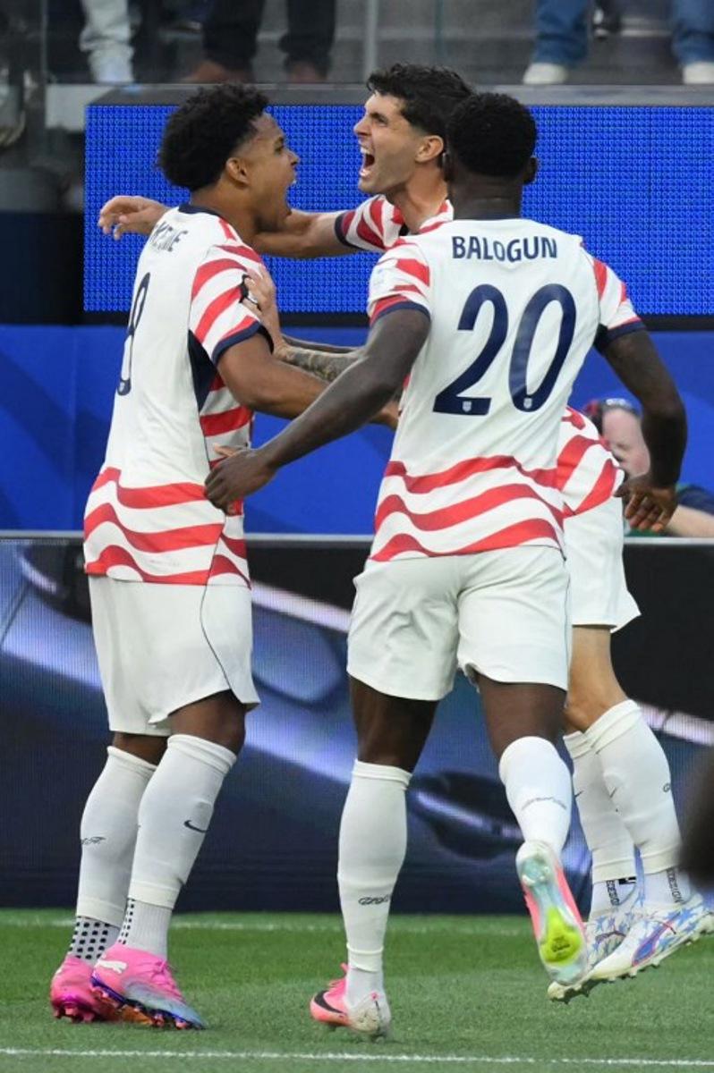 US forward #10 Christian Pulisic (C) celebrates with teammates after his team's first goal scored on own goal by Paraguay's midfielder #16 Damian Bobadilla (unseen) during the 2026 World Cup Group D football match between USA and Paraguay at the Los Angeles Stadium in Inglewood on June 12, 2026. Patrick T. Fallon / AFP