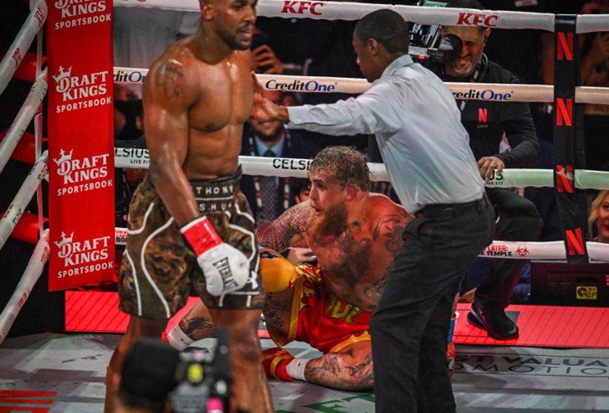 Referee Christopher Young counts over US boxer and influencer Jake Paul as he sits on the floor during his fight against British boxer Anthony Joshua (L) in a non-title heavyweight bout at the Kaseya Center in Miami, Florida, on December 19, 2025. Giorgio VIERA / AFP