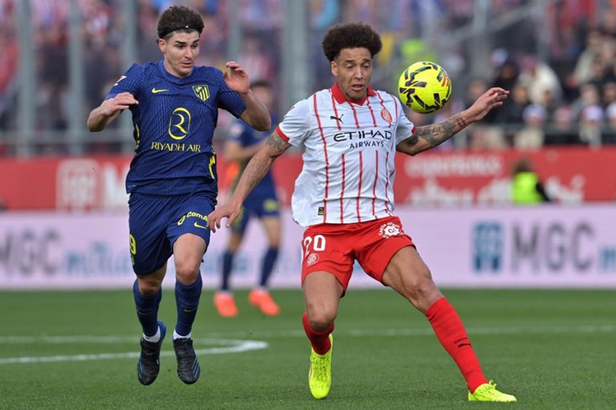 Atletico Madrid's Argentine forward #19 Julian Alvarez (L) and Girona's Belgian defender #20 Axel Witsel fight for the ball during the Spanish league football match between Girona FC and Club Atletico de Madrid at Montilivi Stadium in Girona on December 21, 2025. MANAURE QUINTERO / AFP
