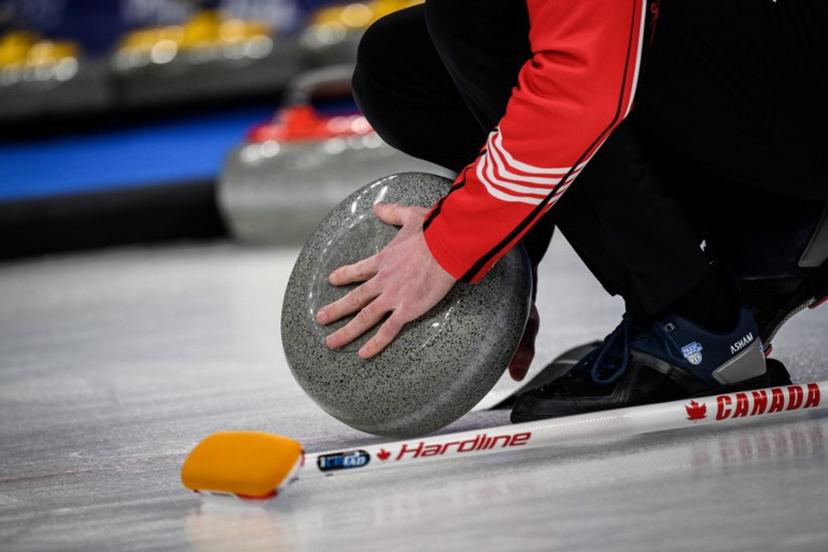 A Canada team member checks on the curling stone during the men's bronze medal game of the Beijing 2022 Winter Olympic Games curling competition between Canada and USA at the National Aquatics Centre in Beijing on February 18, 2022. Jeff PACHOUD / AFP