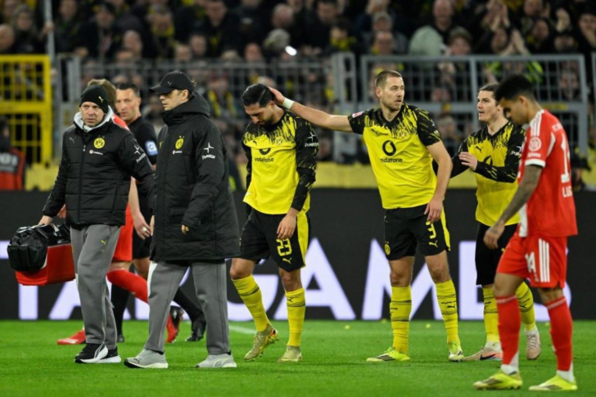 Dortmund's German midfielder #23 Emre Can (C) is consoled by his teammates including Dortmund's German defender #03 Waldemar Anton as he goes off after sustaining an injury during the German first division Bundesliga football match between BVB Borussia Dortmund and FC Bayern Munich in Dortmund, western Germany, on February 28, 2026. INA FASSBENDER / AFP