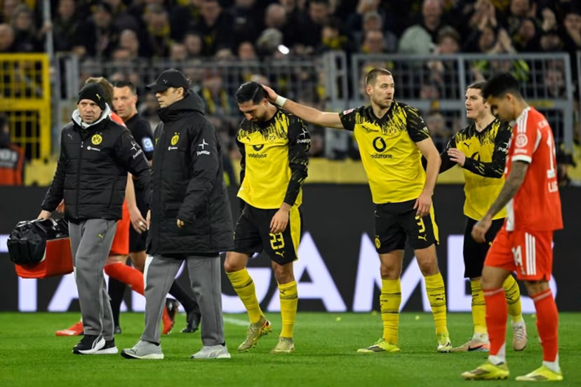 Dortmund's German midfielder #23 Emre Can (C) is consoled by his teammates including Dortmund's German defender #03 Waldemar Anton as he goes off after sustaining an injury during the German first division Bundesliga football match between BVB Borussia Dortmund and FC Bayern Munich in Dortmund, western Germany, on February 28, 2026. INA FASSBENDER / AFP